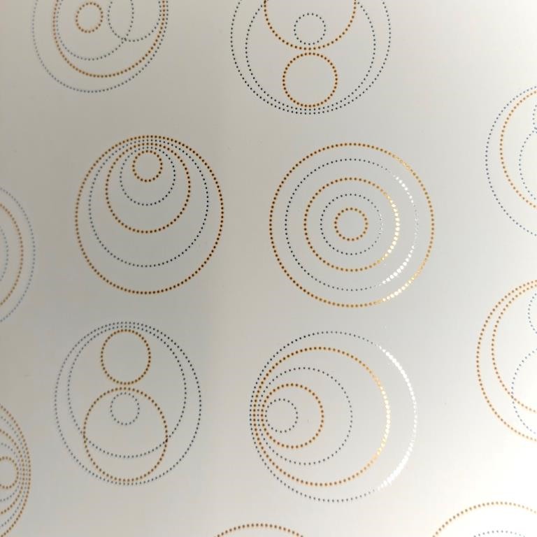 Geschenkpapier mit spiegelglänzenden Punkten in Kreisform auf mattcremefarbenem Hintergrund.
 